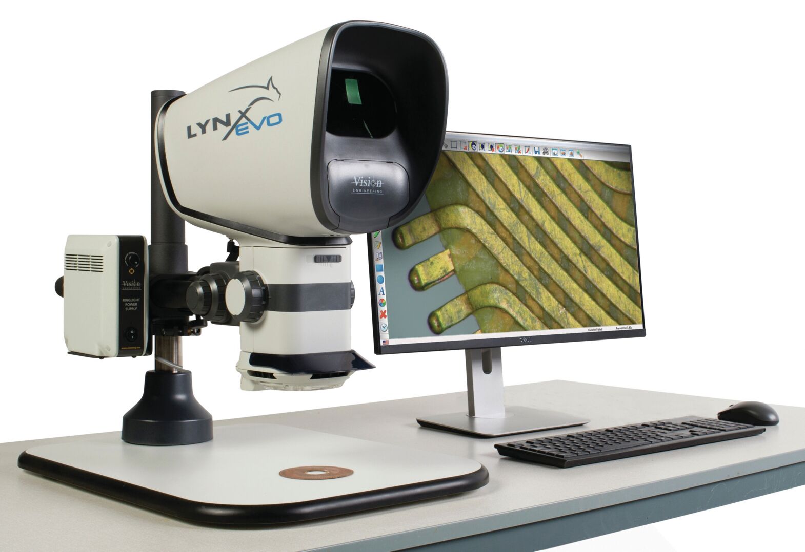 The image shows a digital microscope with a large lens and a monitor. Detailed images of fine structures are visible on the screen. There is a keyboard and mouse.