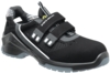 Preview: The image shows a black, sporty safety shoe with two wide Velcro straps. The shoe has a textured sole and breathable elements. It appears sturdy and functional.