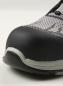 Preview: The image displays the front of a sports shoe. The toe cap is black and prominent, while the upper is made of gray, mesh-like material. The texture is smooth.