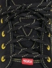 Preview: The image shows the laces of a black shoe. The laces are black with yellow accents, and a small red label is visible on the shoe.