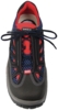 Preview: The image displays a sports shoe. It is primarily black with red and blue accents. The shoelaces are black, and the shoe features a thick, grippy sole. The design appears functional and modern.