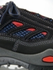 Preview: The image shows a sport or hiking shoe in black with blue and red accents. The shoe features mesh material for ventilation and a sturdy, gray sole with stabilizing elements.