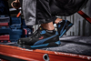 Preview: The image shows a foot in a black PUMA safety shoe with blue accents, standing on a red work surface. Toolboxes are visible in the background.