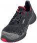 Preview: The shoe is a sports or running shoe in black with a textured surface. It has red accents and a gray, soft toe area. The laces are elastic and ensure a secure fit.