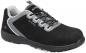 Preview: The image shows a black safety shoe with a gray trim. It has a flat sole, laces, and a reinforced toe cap for protection. The surface is made of durable material.