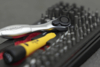 Preview: The image shows various tools. A silver ratchet lies next to a yellow screwdriver, surrounded by many black bits arranged in a red holder.