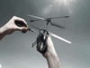 Preview: A person is holding a small model helicopter and is screwing on one of the rotors with a screwdriver. The background is bright and neutral.