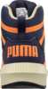 Preview: Das Bild zeigt die Rückansicht eines Sportschuhs in Dunkelblau mit orangefarbenen Akzenten. Der Markenname "PUMA" ist auffällig groß auf der Ferse eingeprägt. Der Schuh hat eine robuste, helle Sohle.