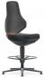 Preview: The image shows a modern office chair in black with a high backrest. It has a round footrest and a central pillar. An orange accent is visible on the side.