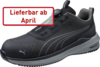 Preview: Das Bild zeigt einen schwarzen Sportschuh mit einem modernen Design. Er hat eine strukturierte Oberfläche und ist mit einem Obermaterial aus Mesh ausgestattet. An der Seite befindet sich das Puma-Logo. In rotem Text steht "Lieferbar ab April".