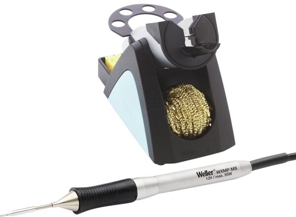 The image displays a soldering iron set. A soldering station with a black cover and a golden cleaning sponge. Next to it lies the silver soldering iron with a rubberized handle and a fine tip.