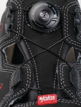 The image shows a black shoe with a special lacing system. In the center, there is a round rotary closure that tightens the laces. The sole reads "jalas."