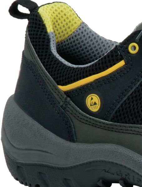 The image shows a part of a shoe. It is predominantly black with gray and yellow accents. The surface appears textured, and the sole is designed to be stable and robust.