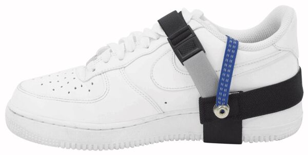 The image shows a white sneaker with a black and blue holder on the side. The holder appears to have a special function, possibly a support or securing feature.