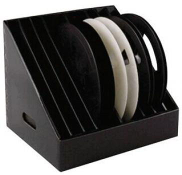 The image shows a slanted, black storage container with several round, flat plates inside. Two plates are white and several are black. Ideal for organizing.