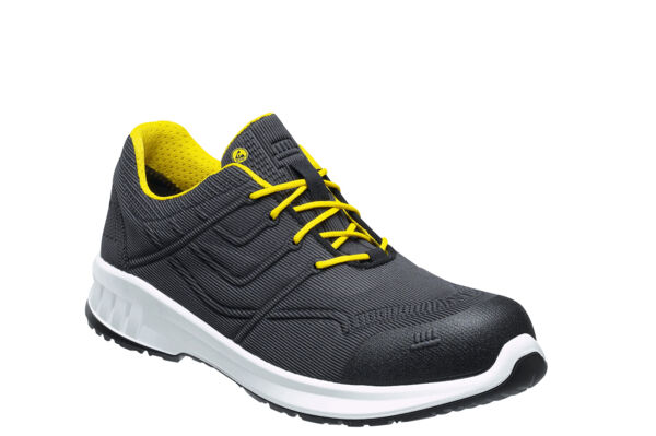 The shoe is sporty and made of black material with a textured design. The laces are bright yellow, and the sole is white with a black bottom.