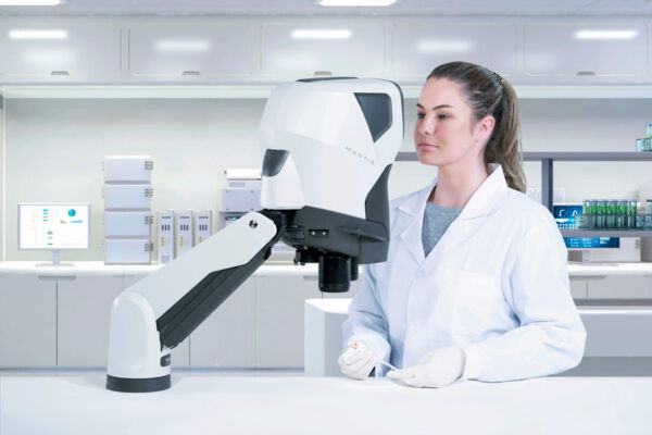 The image shows a female lab technician in a white coat, working intently on a futuristic robotic device. Laboratory equipment can be seen in the background.