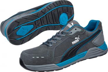 The image shows athletic shoes in gray with blue accents. They have a flat, textured sole and lacing. The Puma logo is visible. The shoes appear modern and functional.