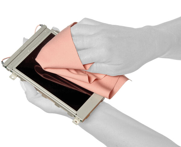 Two hands hold a screen frame. One hand wipes over the surface of the screen with a pink cloth to clean it. The background is neutral and solid-colored.