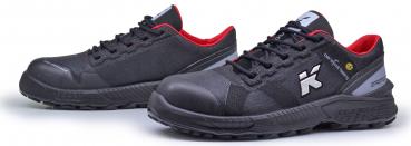 The image shows a pair of black safety shoes with red accents. They have a sturdy, non-slip sole and laces. A logo is visible on the side.