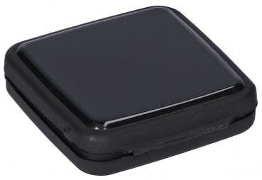 The image shows a small, square, shiny black container with rounded edges. The surface is smooth and reflects light. It appears compact and simple.