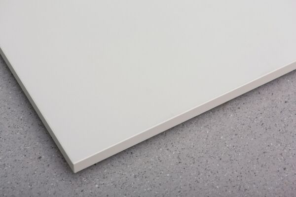 The image displays a bright, smooth plate at a right angle. The surface is white and slightly reflects the light, while the background is gray and textured.