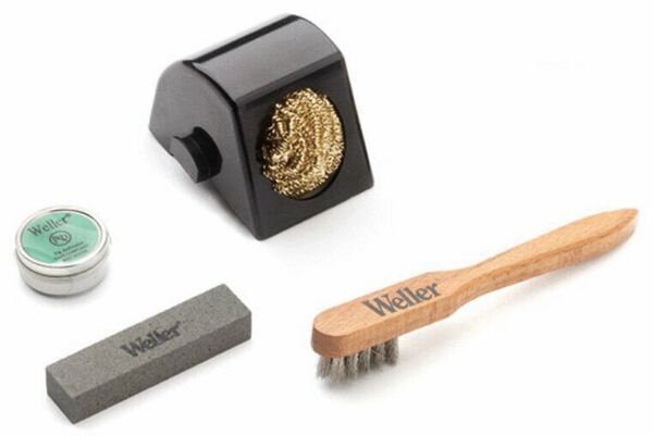 The image shows four tools: a black soldering station with a golden spiral, a round can with green contents, a gray grinding stone, and a wooden brush with metal bristles.