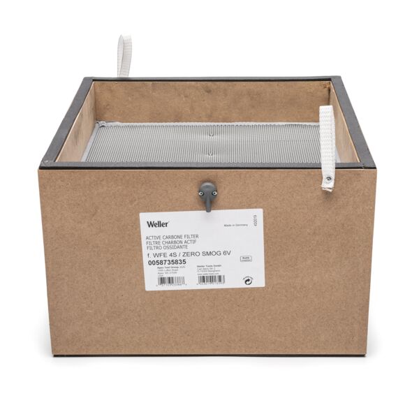 The image shows a square, brown cardboard box with a fine grid on the top. On the front side, there is a label with information and a small handle.