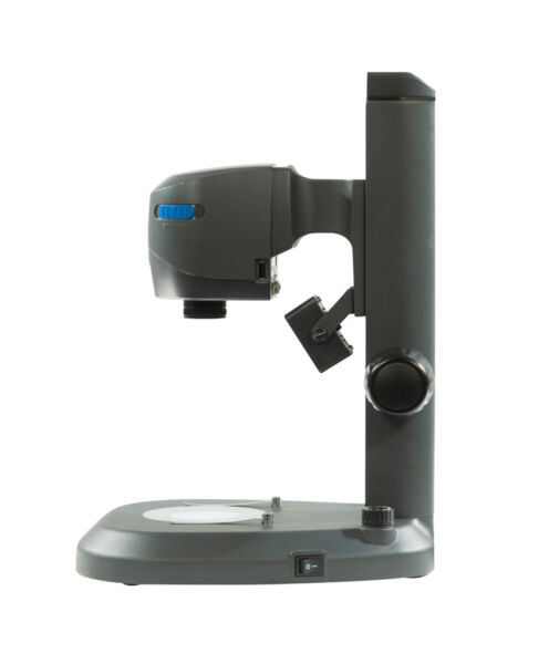 The image shows a gray microscope. It has a round base with a round opening in the middle. The lens is mounted on an arm that points diagonally downward. On the right is a rotary knob.