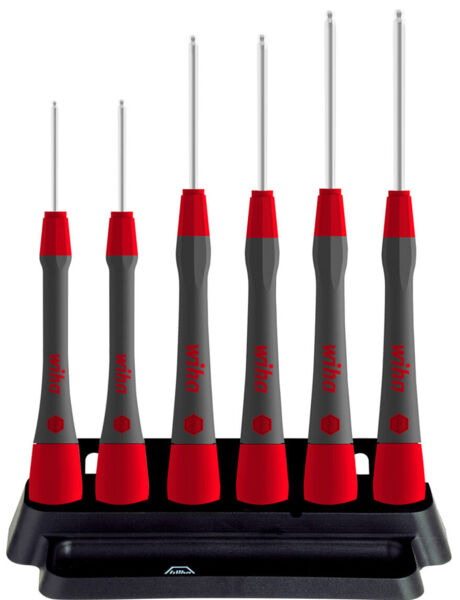 The image shows six screwdrivers in a holder. The handles are red and gray, the blades are long and silver. They are neatly lined up on a black base.