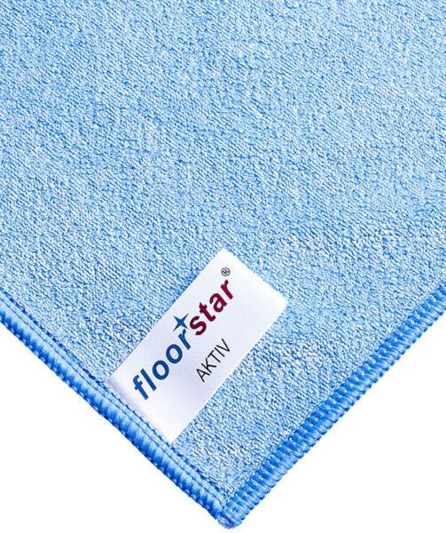 The image displays a light blue microfiber cloth with a textured surface. In one corner, the label 