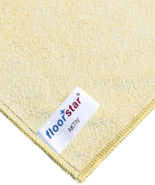 The image shows a light beige cleaning cloth with a labeled corner. The label features the word 