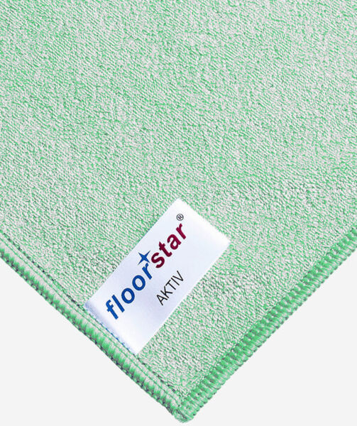 The image displays a section of a green cleaning cloth with a label. The label reads 