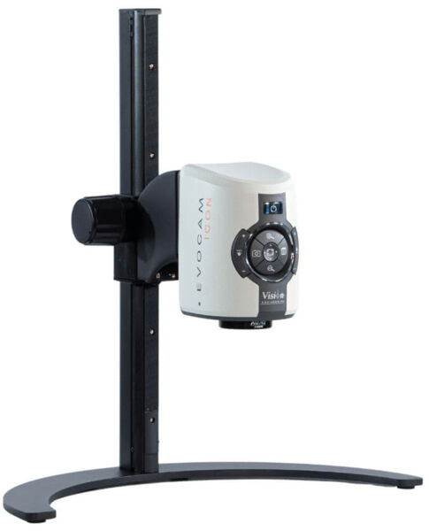 The image shows a device with a rectangular body, a large lens at the front, and buttons on the front side. It is mounted on a stable, round base and attached to a vertical stand.