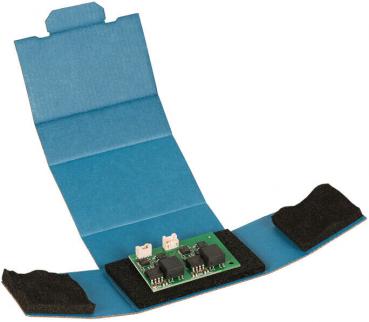 The picture shows a flat, blue package that is open. Inside, there is a green circuit board with several black components and connectors, surrounded by black foam.