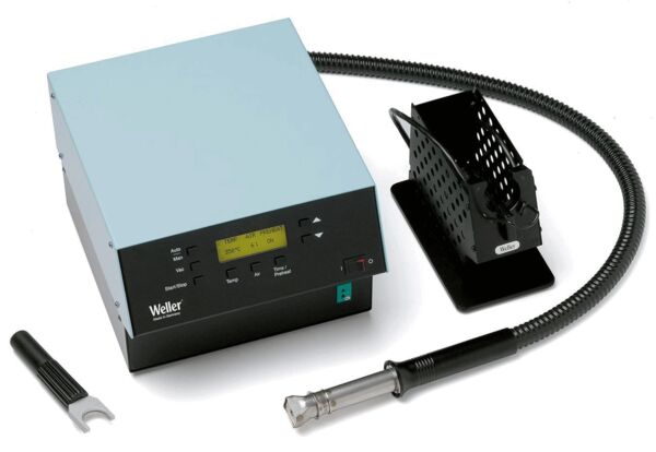 The image shows a soldering station with a rectangular base, a display, and controls. A flexible hose leads to a soldering iron, next to which is a wire mesh holder. A tool is lying beside it.