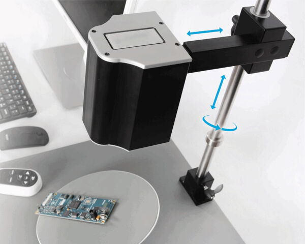 The image shows a technical workstation with a camera hovering over a circular area. Below it is a circuit board. The camera can be moved in various directions.