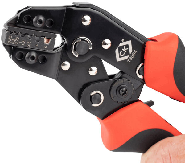 The image shows a combination pliers with red and black handles. The pliers have a central cutter and several adjustment options for cable cross-sections. It is held in a hand.