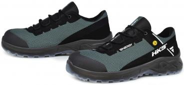 The image shows a pair of athletic shoes in black and gray. They have a padded sole and a breathable upper with laces. The design appears sturdy and functional.