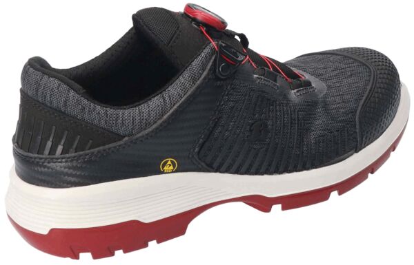 The shoe is sporty and modern, primarily black with gray and red accents. It has a textured surface, quick lacing, and a sturdy, two-tone sole.