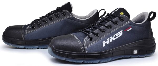 The image shows a pair of black athletic shoes. They have a sturdy, non-slip sole and a breathable, reinforced upper. The laces are black, and on the side is "HKS".