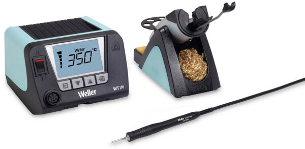 The image shows a soldering station with a digital display and controls. Next to the station, there is a soldering tip in a holder. A sponge for cleaning is also included.