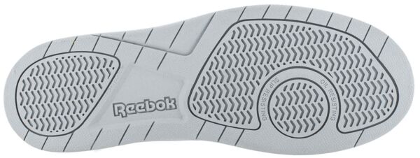 The image displays the underside of a gray Reebok sole. It features a tread with various patterns, molded grooves, and a circular area in the center. The brand name "Reebok" is visible.