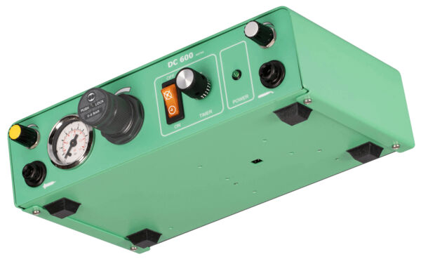 The image shows a green, rectangular device with various controls. There is a rotary knob, a pressure gauge, and switches. On the side, there are rubber feet.