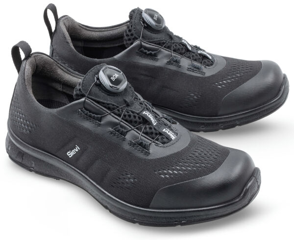 The image shows a pair of black athletic shoes. They are made from durable material, have a flexible sole, and feature an innovative closure mechanism with a round button.