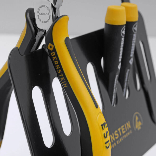 The image shows a tool fork with a pair of pliers that have yellow and black grip areas. Next to it are three black markers with yellow caps on a black holder.