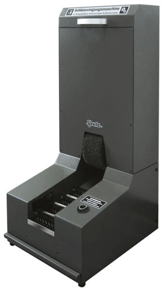 The image shows a black shoe cleaning machine. It features a tall, rectangular shape with an upper compartment and a wide opening at the bottom. Inside, there are brushes for cleaning shoes.