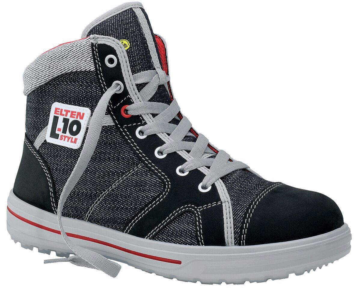 The shoe is a tall, sporty safety boot made of black material with gray textile. It has white laces, a sturdy rubber sole, and a red-white brand sticker.