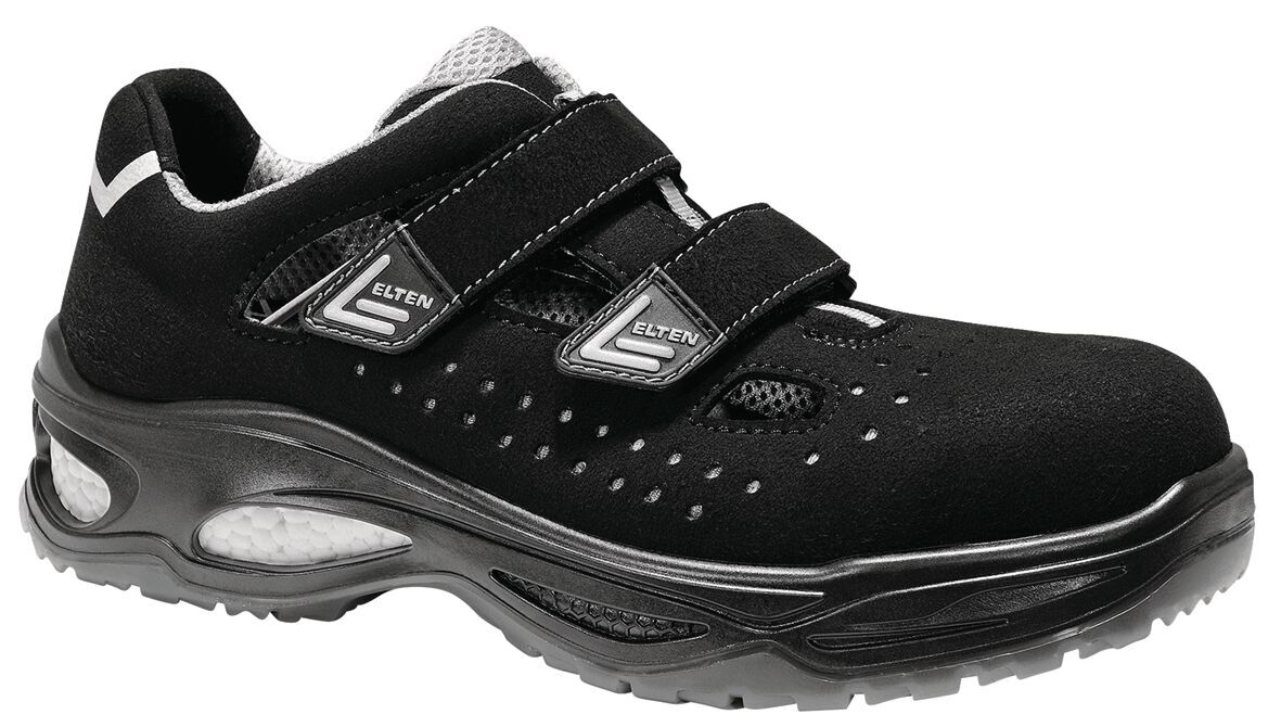 The image shows a black work shoe with two Velcro straps. The shoe has a breathable upper with small holes and a sturdy, non-slip sole.