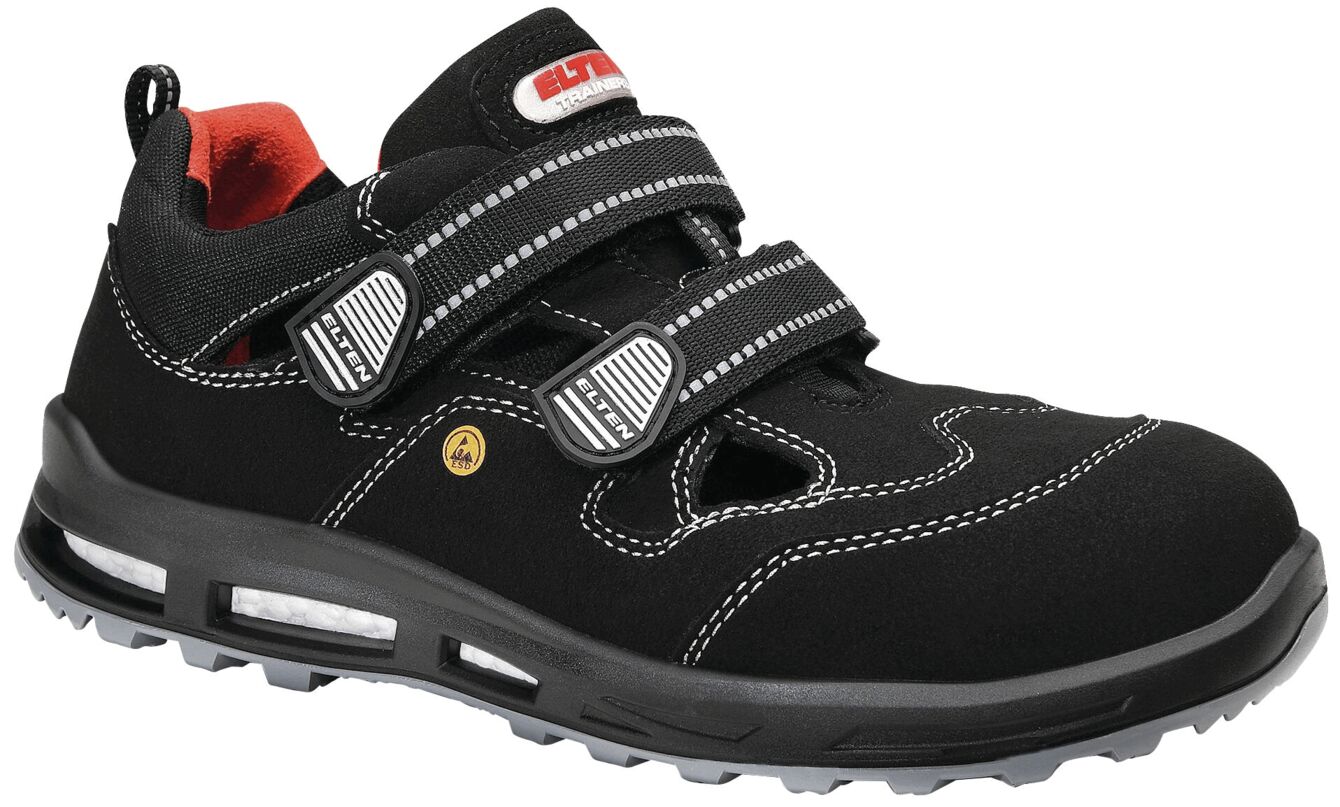 The shoe is black with red accents and is made of a durable material. It has two wide Velcro straps and a non-slip treaded sole.